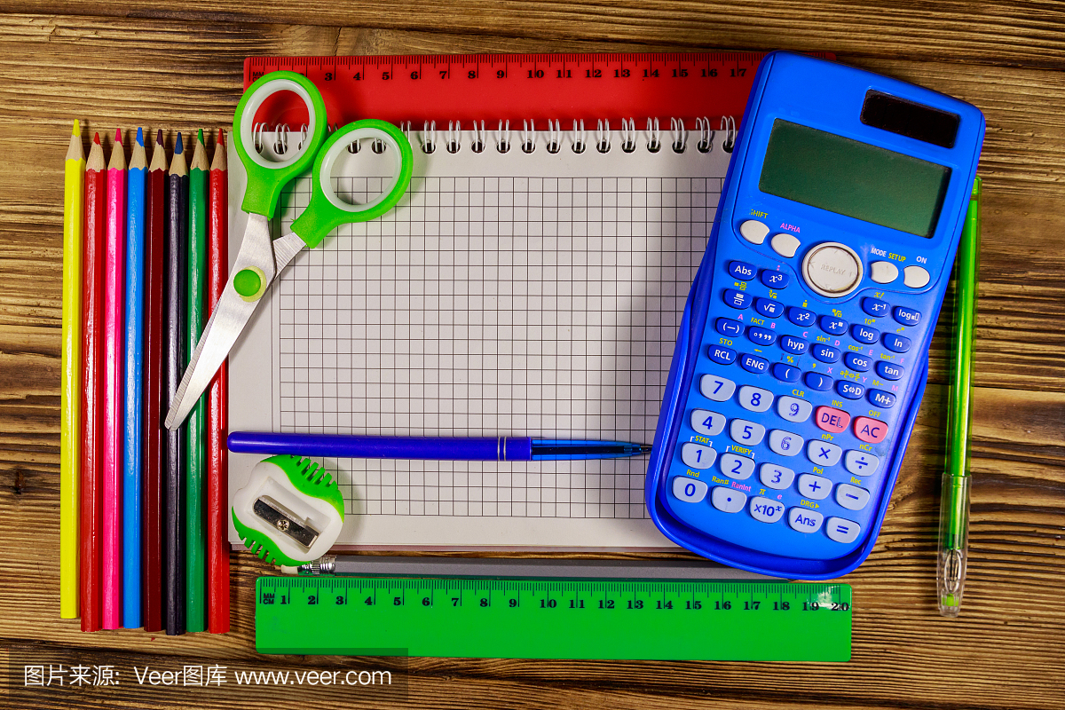 整套學(xué)校文具用品。空白記事本,計(jì)算器,尺子,鉛筆,鋼筆,剪刀和卷筆刀放在木桌上。俯視圖